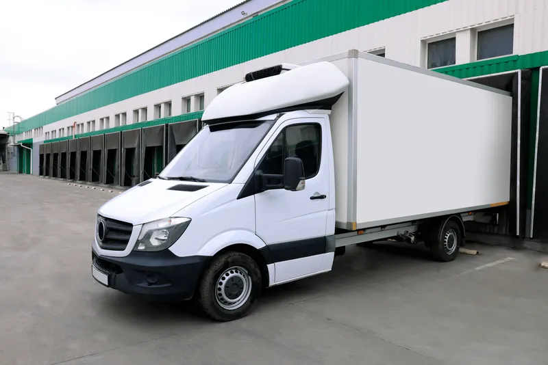 Refrigeration truck body with insulated cargo box parked at warehouse loading dock for cold chain delivery